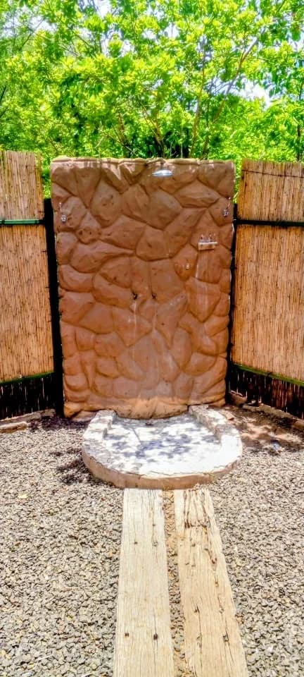 Outdoor shower with a rock-effect wall and reed screens