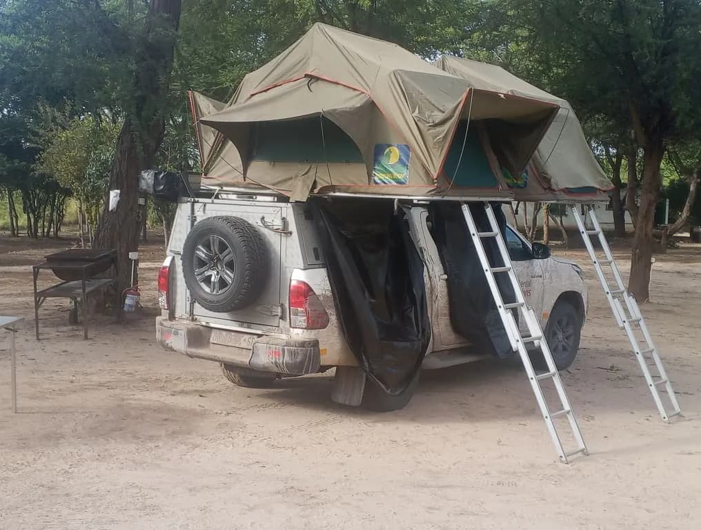 4x4 with an open rooftop tent and ladders on the campsite