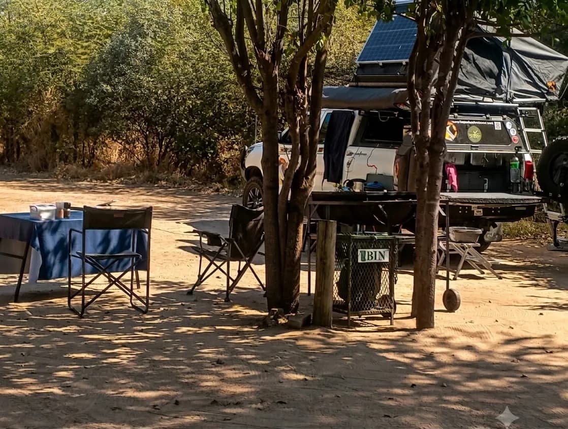 Camp chairs in the dappled shade beside a 4x4 on the campsite