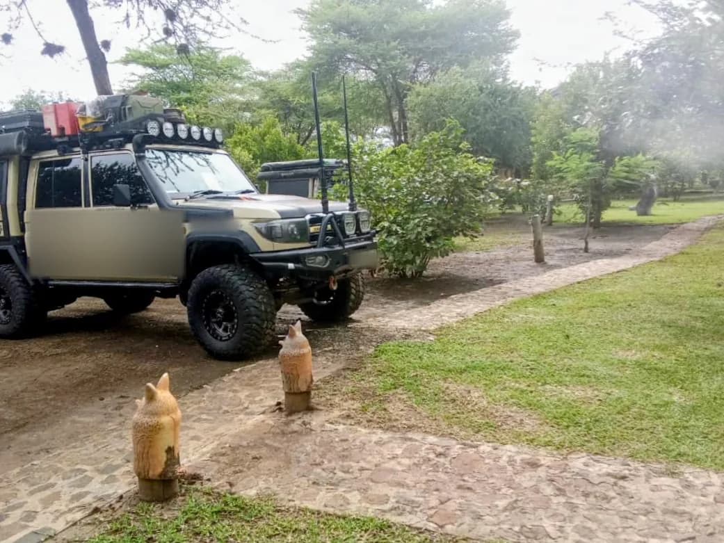 Expedition Land Cruiser beside the stone path, with carved owl posts in the foreground