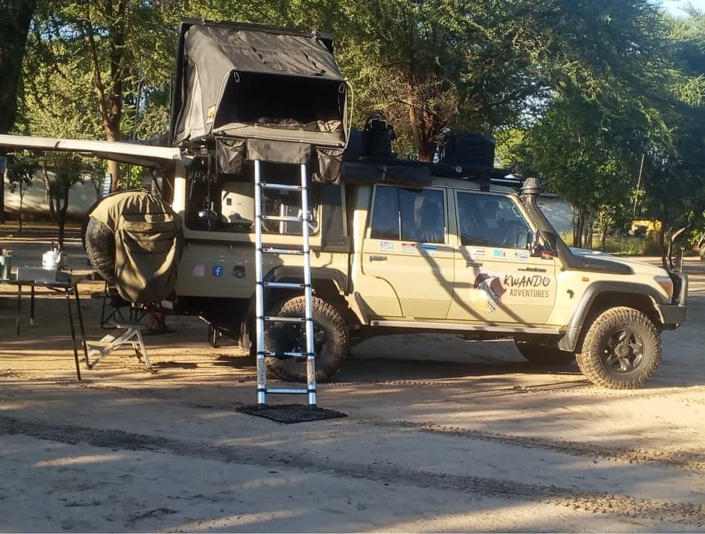 Land Cruiser with a rooftop tent and ladder on the campsite