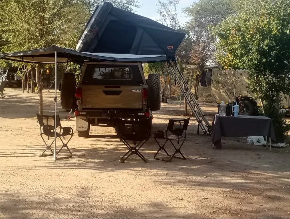 Pickup with a rooftop tent and side awning, camp chairs set out