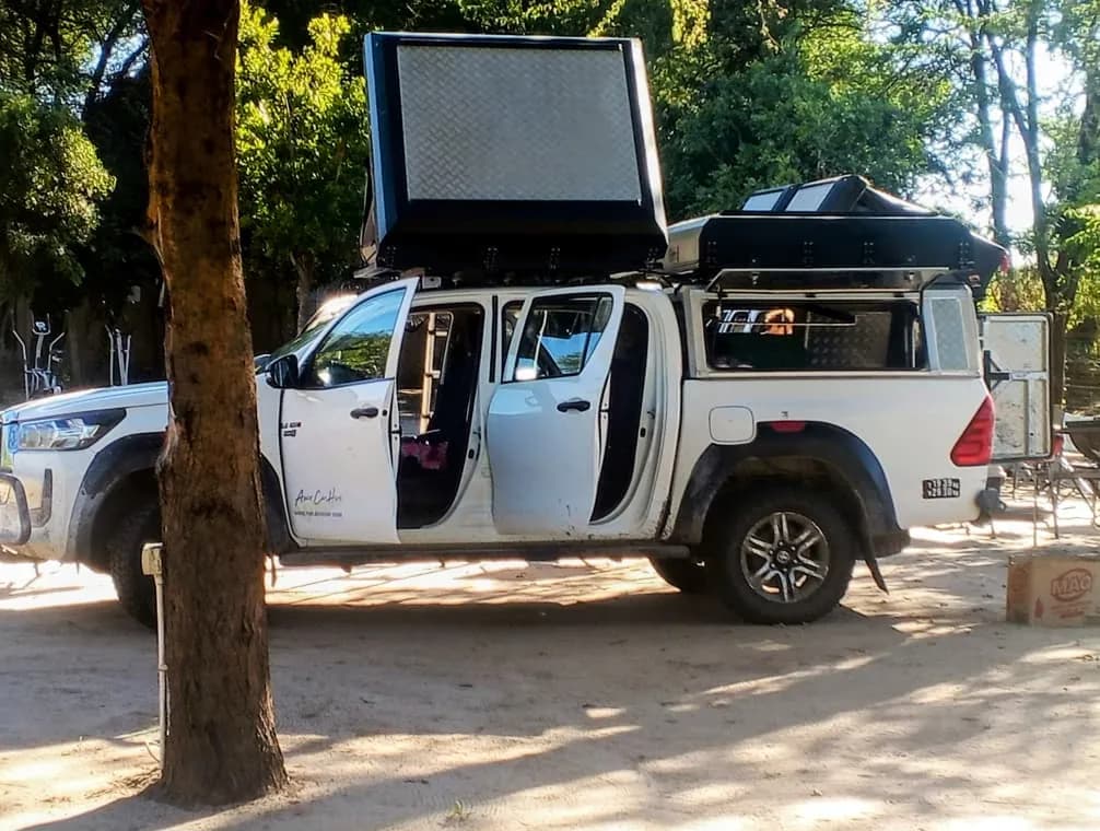 White pickup with a rooftop tent parked under the trees