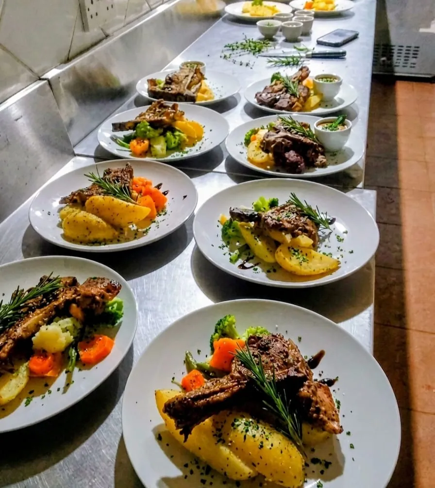 Plated lamb dinners lined up on the pass in the kitchen