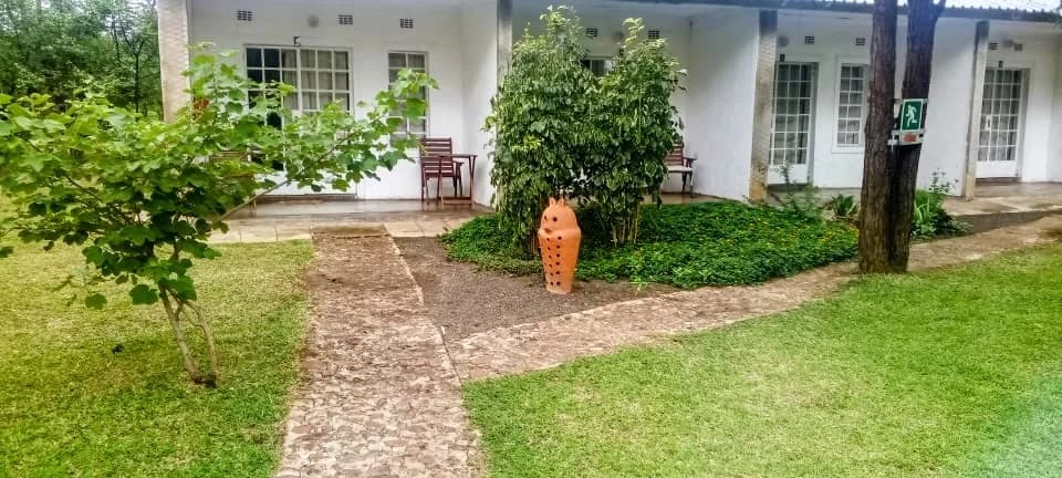 Lodge rooms with a stone path, a clay pot and garden chairs on the veranda
