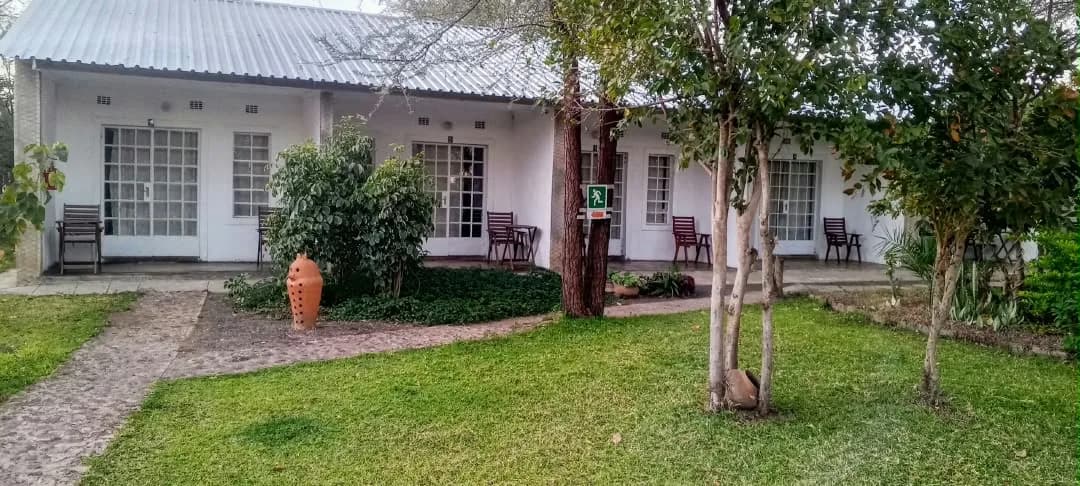 Row of lodge rooms with garden chairs on the veranda and a lawn in front