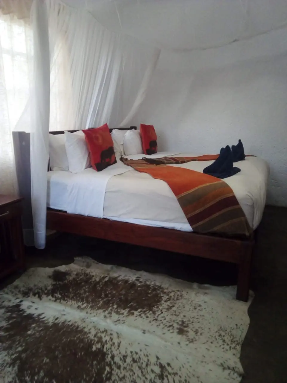 Room with a double bed, mosquito net and cowhide rug